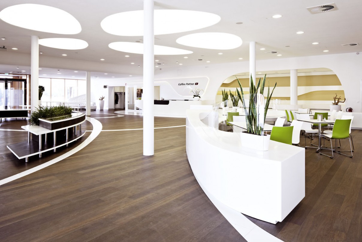 Heller, modern eingerichteter Eingangsbereich mit dunklem Designboden, wei&szlig;en M&ouml;beln und gr&uuml;nen Akzentst&uuml;hlen