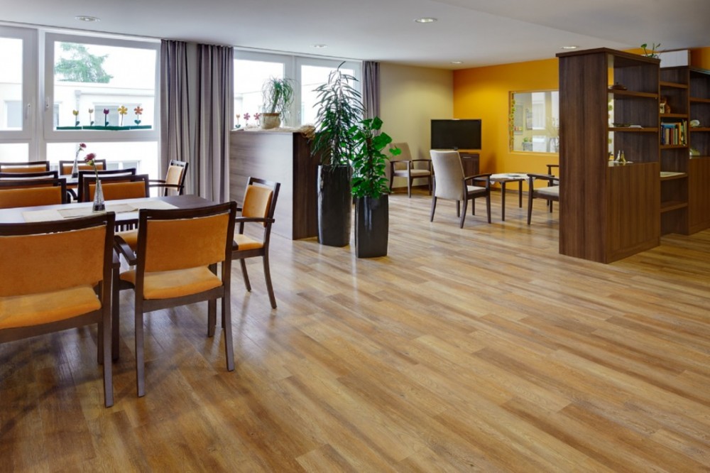 Wohn- und Aufenthaltsbereich mit Designbelag in Holzoptik, Sitzgruppen und dekorativen Elementen